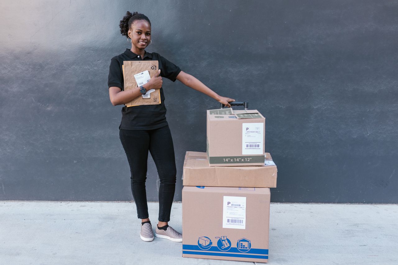 Confident woman holding delivery packages against a modern backdrop.